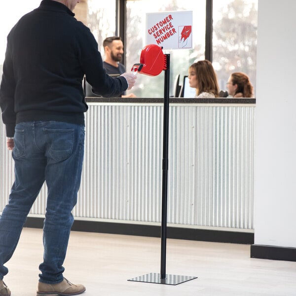 A man in a black sweater and jeans holding a red Garvey My Turn sign.