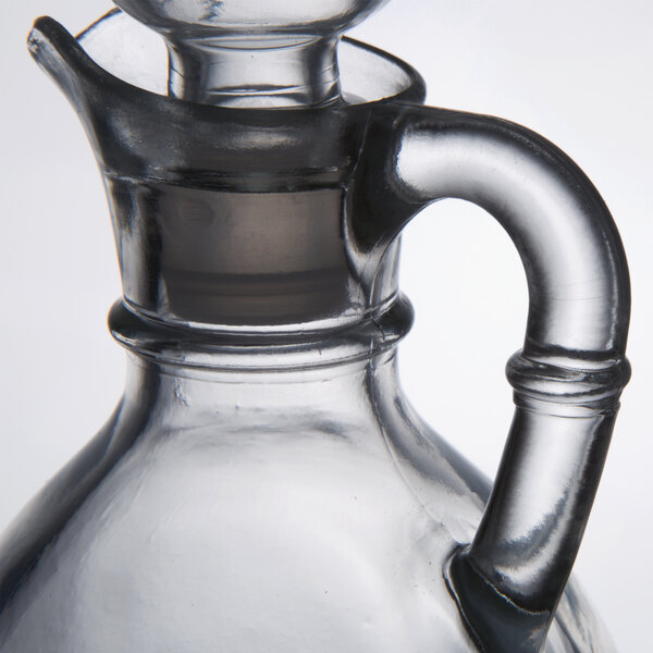 A clear glass Libbey cruet with a handle and stopper.
