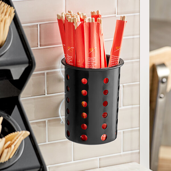 A black container with holes holding utensils.