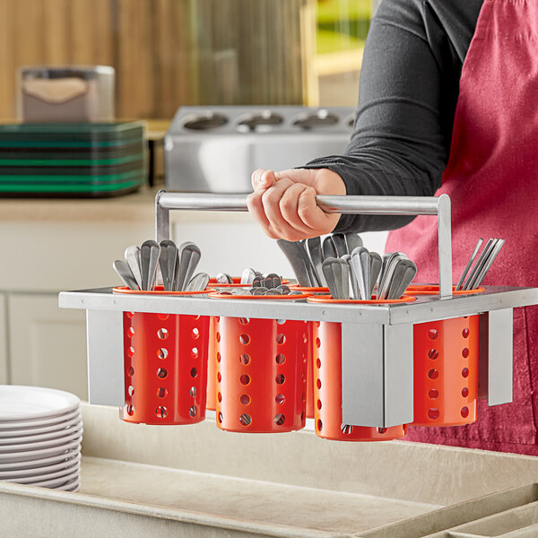 A woman holding a metal rod with orange plastic cylinders holding utensils.