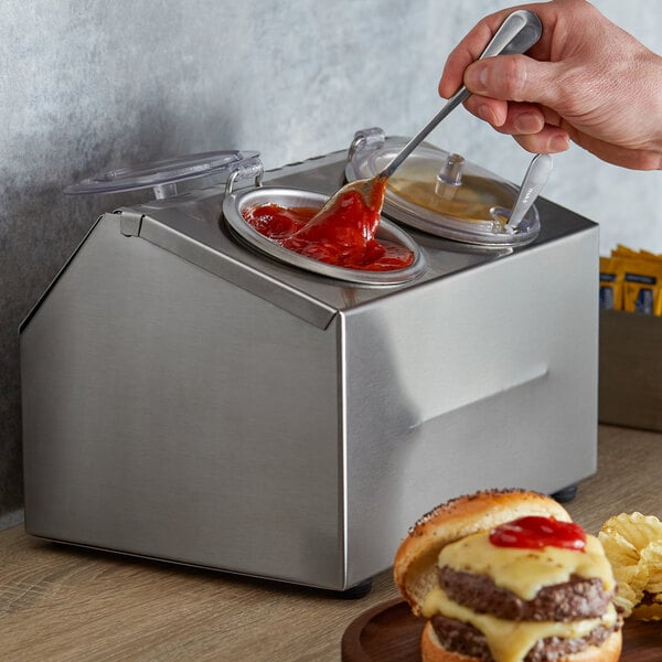 A person pouring sauce into a Steril-Sil condiment container on a counter.