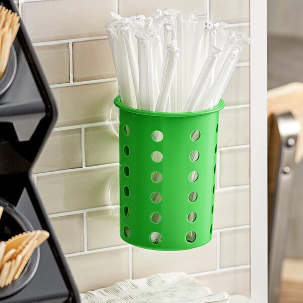 A lime green plastic container with holes holding straws.