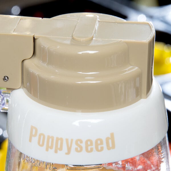 A close up of a white Tablecraft salad dressing dispenser collar with beige lettering that says "Poppyseed"