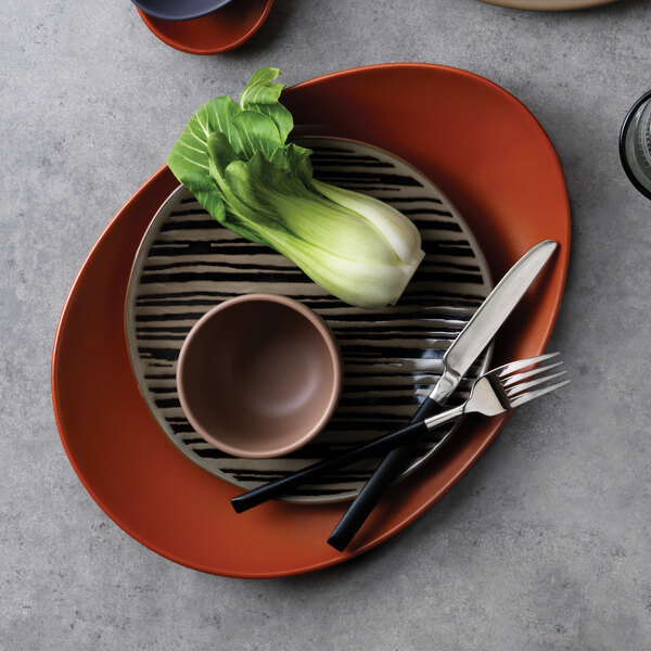 A close-up of a World Tableware Tan Stoneware Salad Plate with a knife and fork on it.