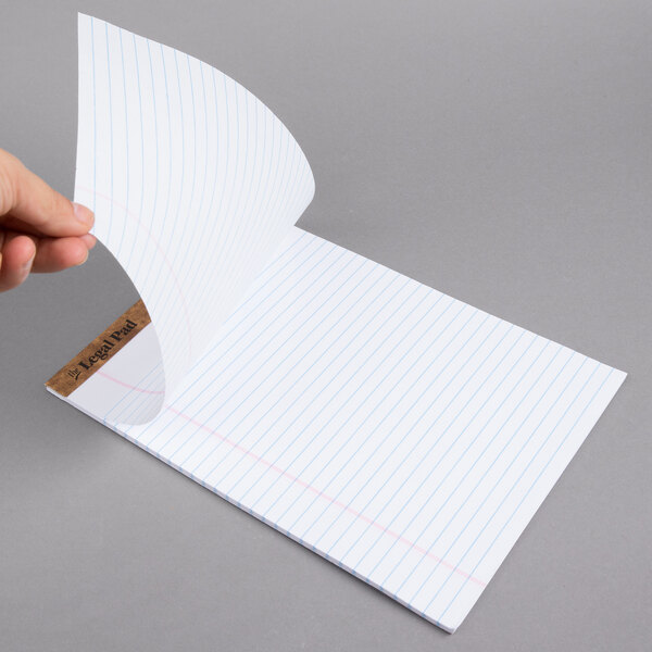 A hand holding a piece of wide ruled paper from a TOPS legal pad.