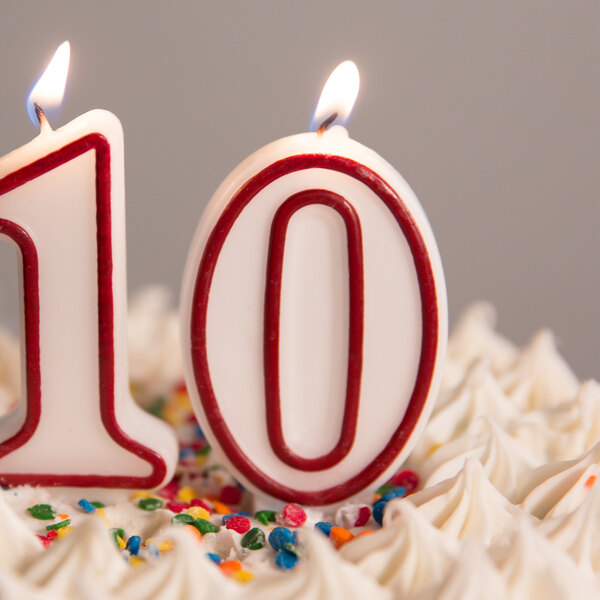 A close up of a white cake with a red and white outlined number 0 candle.