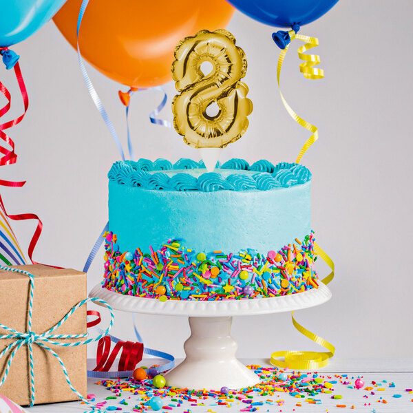 A white birthday cake with a gold number 8 balloon on top.