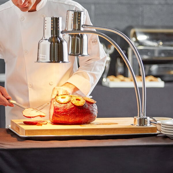 A chef using an Avantco carving station to slice meat.