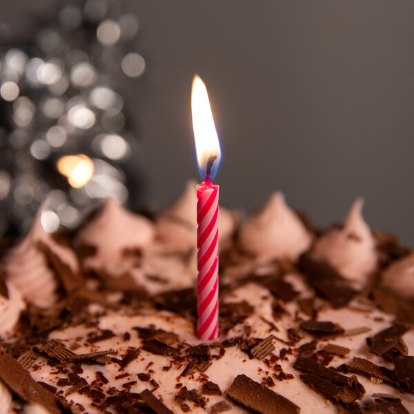 A pink spiral Creative Converting birthday candle on a cake.