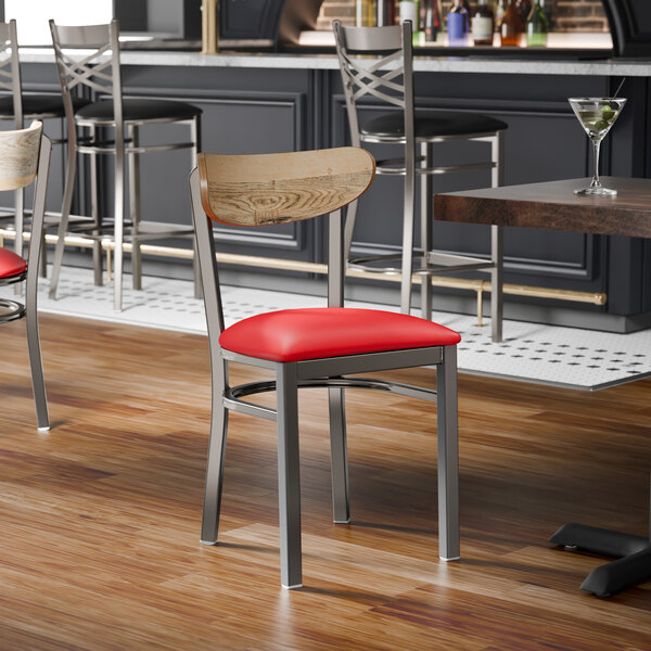 A metal chair with a red vinyl seat and a driftwood-finished wooden backrest.