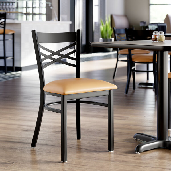 A black metal cross back chair with a light brown vinyl padded seat.