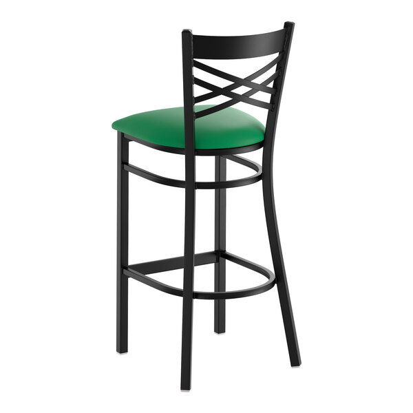 A black metal bar stool with a cross back design and a green vinyl padded seat.