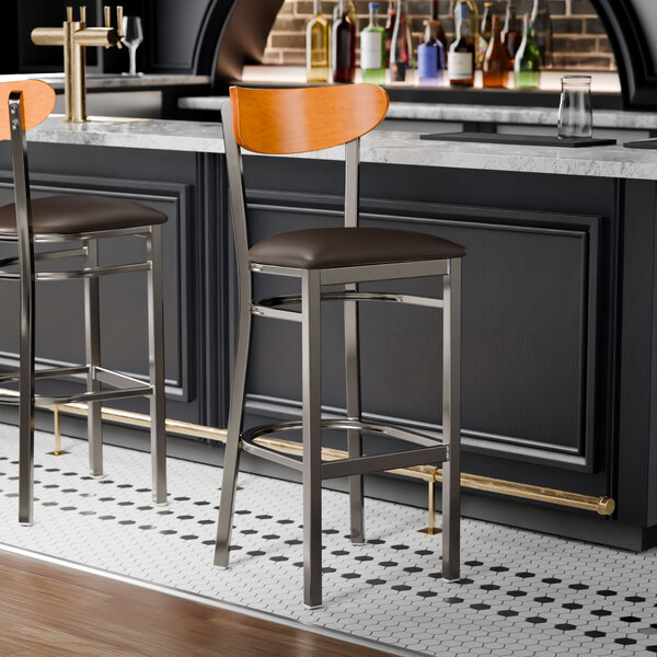 Two Lancaster Table & Seating Boomerang bar stools with dark brown vinyl seats at a bar counter.