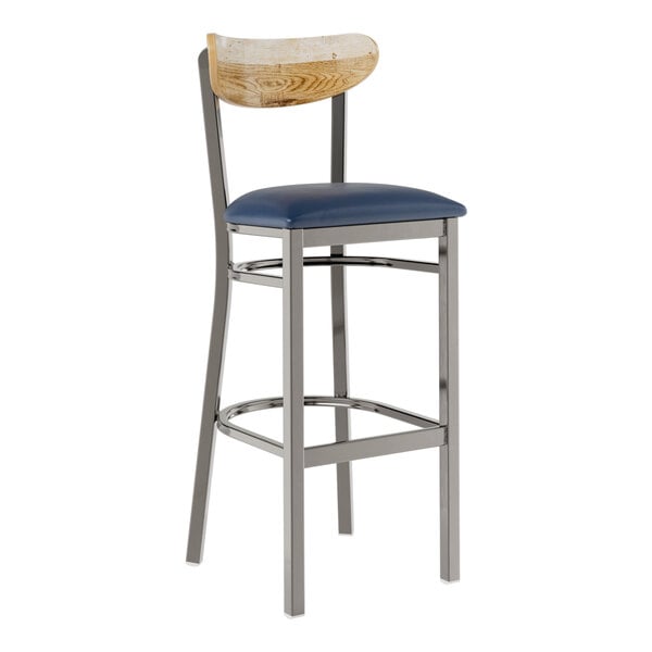 A Lancaster Table & Seating metal bar stool with a blue vinyl cushion on the seat and driftwood back.