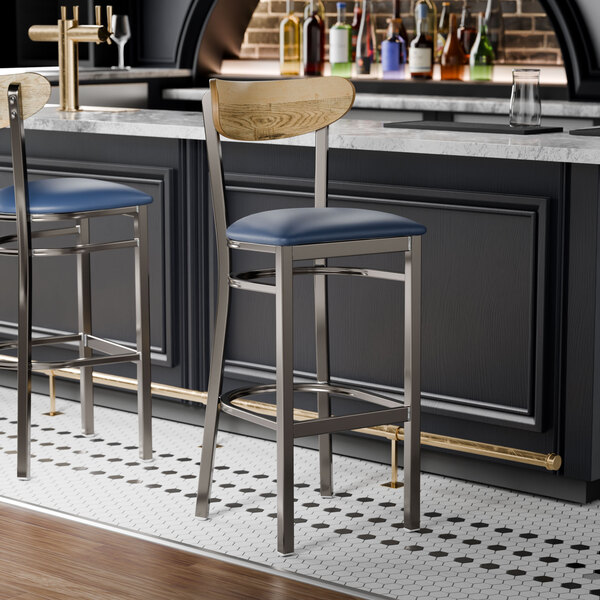 Two Lancaster Table & Seating bar stools with blue vinyl seats and driftwood backs at a black bar counter.