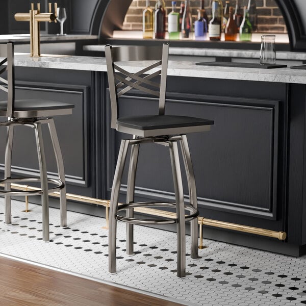 A metal cross back swivel bar stool with a black wood seat and clear coat finish.