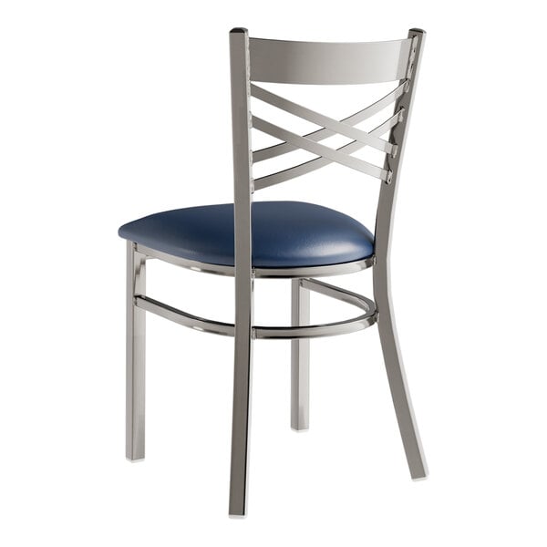A Lancaster Table & Seating metal cross back chair with a navy blue cushion.
