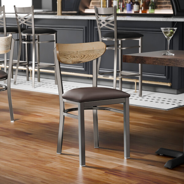 A metal chair with a dark brown vinyl seat and a driftwood-finished wooden backrest.