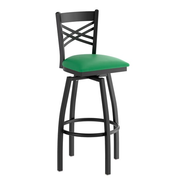 A black metal bar stool with a cross back design and a green vinyl padded swivel seat.