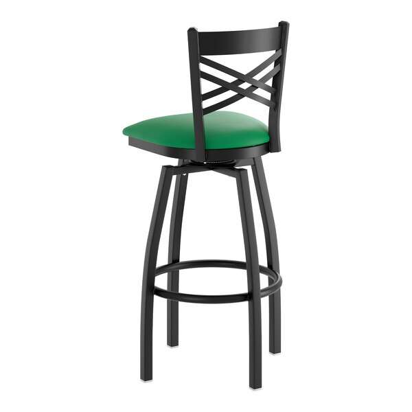 A black metal bar stool with a cross back design and a green vinyl padded swivel seat.