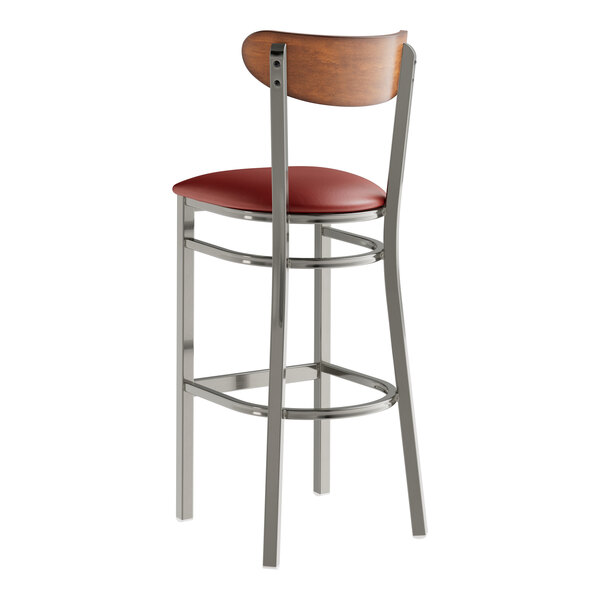 A Lancaster Table & Seating bar stool with a red vinyl seat and wood back.