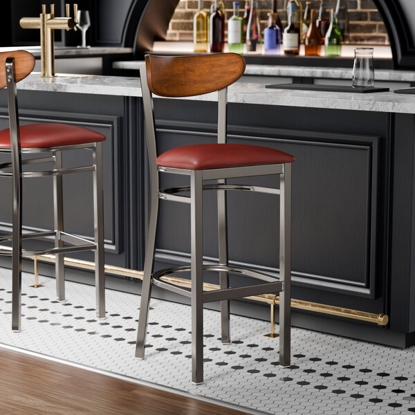 Two Lancaster Table & Seating bar stools with red vinyl seats at a black bar counter.