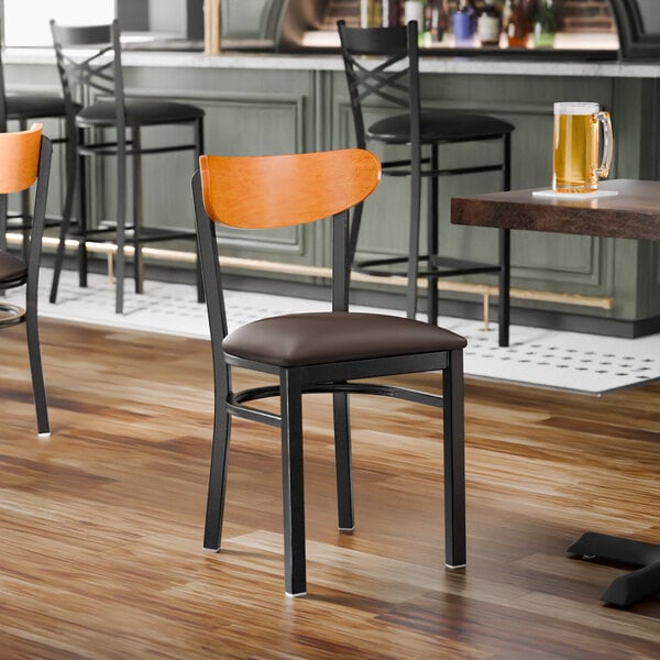 A black metal chair with a dark brown vinyl seat and a cherry wood backrest.