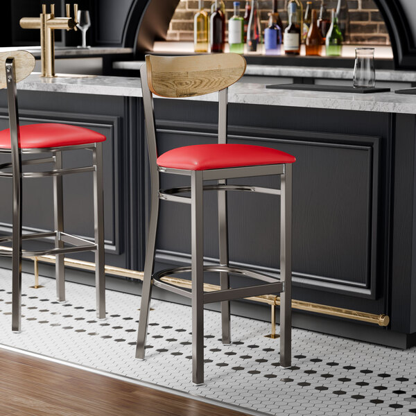 Two Lancaster Table & Seating Boomerang bar stools with red seats and driftwood backs at a bar counter.