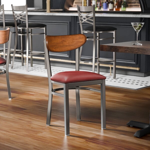 A metal chair with a burgundy vinyl seat and an antique walnut wood backrest.