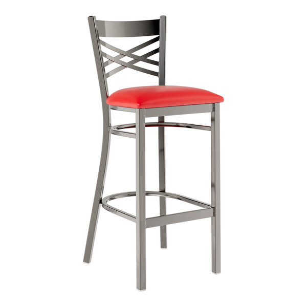 A metal bar stool with a cross back design and a red vinyl padded seat.