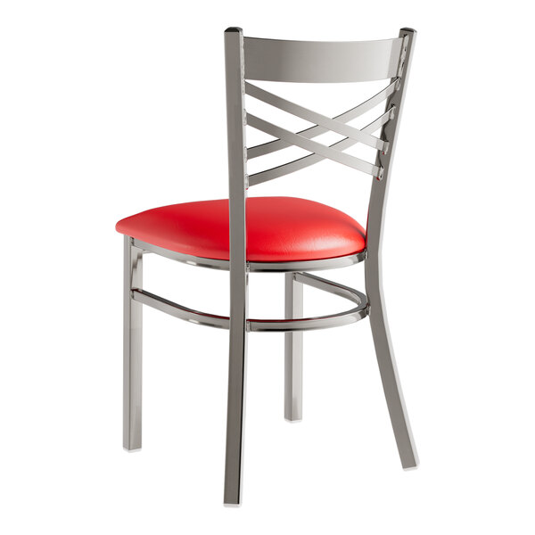 A Lancaster Table & Seating clear coat finish metal cross back chair with a red vinyl padded seat.