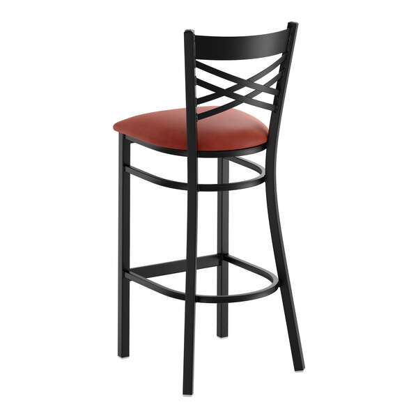 A black metal bar stool with a cross back design and a burgundy vinyl padded seat.