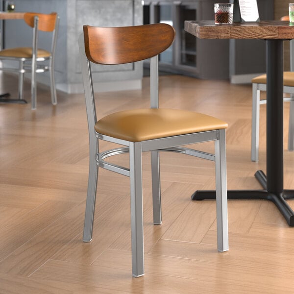 A Lancaster Table & Seating wooden chair with a clear coat finish, light brown vinyl seat, and antique walnut back.