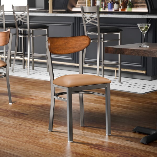 A metal chair with a light brown vinyl seat and an antique walnut wood backrest.