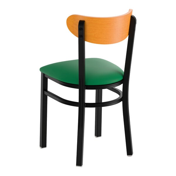A black metal chair with a green vinyl seat and a curved cherry wood backrest.