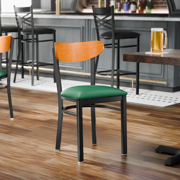 A black metal chair with a green vinyl seat and a cherry wood backrest.