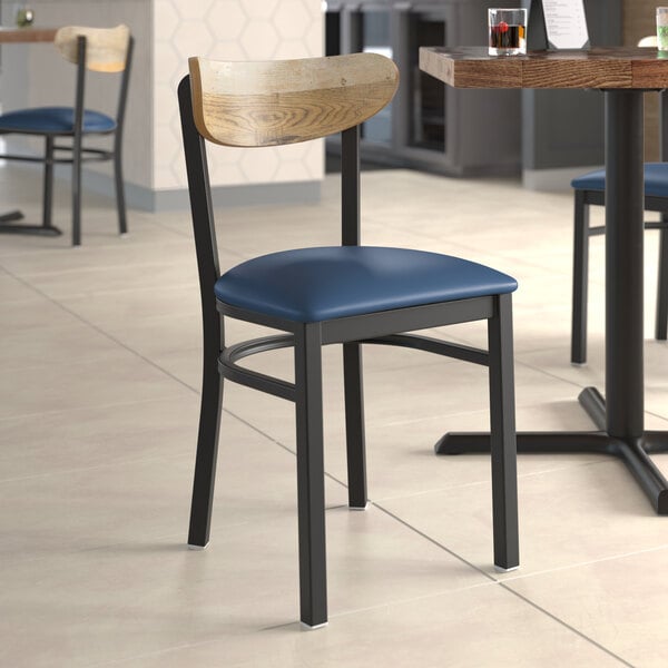 A Lancaster Table & Seating Boomerang chair with a navy cushion and driftwood back on a table in a restaurant.