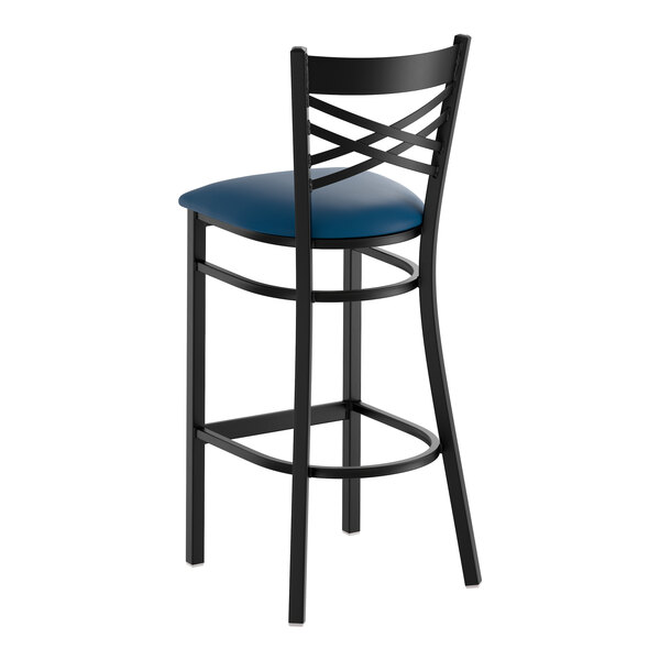 A black metal bar stool with a cross back design and a navy blue vinyl padded seat.