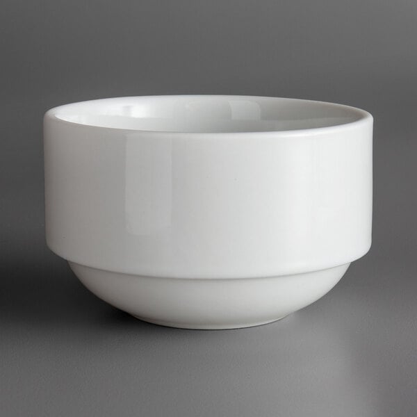 A stackable white porcelain soup bowl with a small rim on a gray surface.