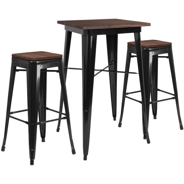 A black rustic galvanized steel table with a wooden top and two black backless stools.