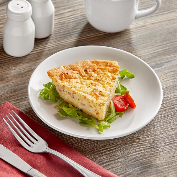 A slice of quiche on an Acopa bright white stoneware plate with a fork.