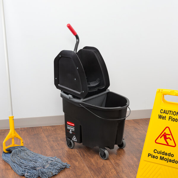 A Rubbermaid Executive Series WaveBrake 35 Qt. mop bucket and wringer on a wood floor.