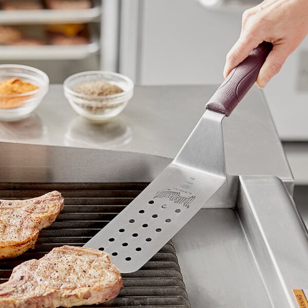 A Mercer Culinary Hell's Handle spatula being used to grill meat.