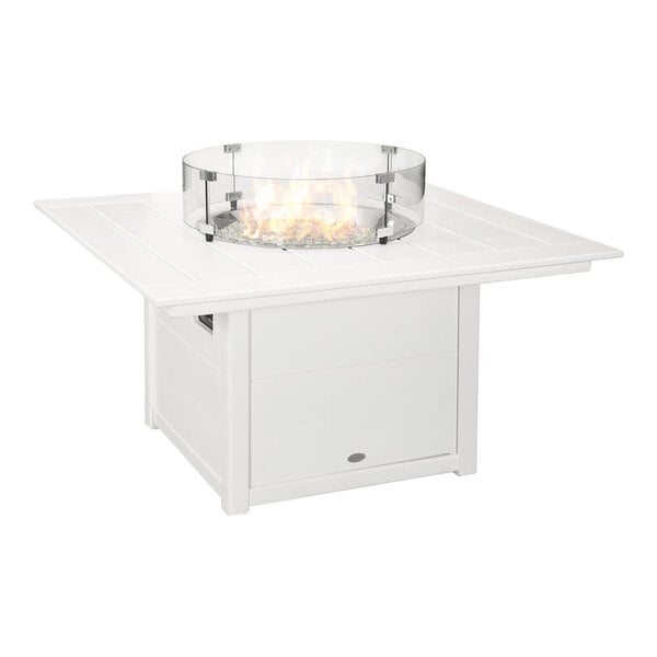 A white square fire pit table with a glass wind guard around the flame area.