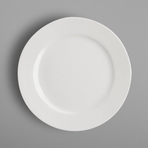 A close-up of a RAK Porcelain ivory wide rim flat plate.