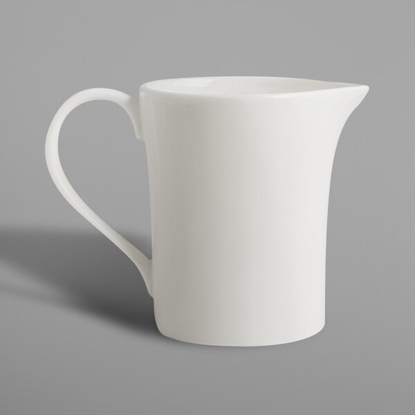 A white RAK Porcelain creamer pitcher with a handle.