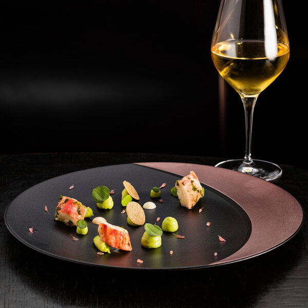 A RAK Porcelain bronze and black deep plate with food on a table.