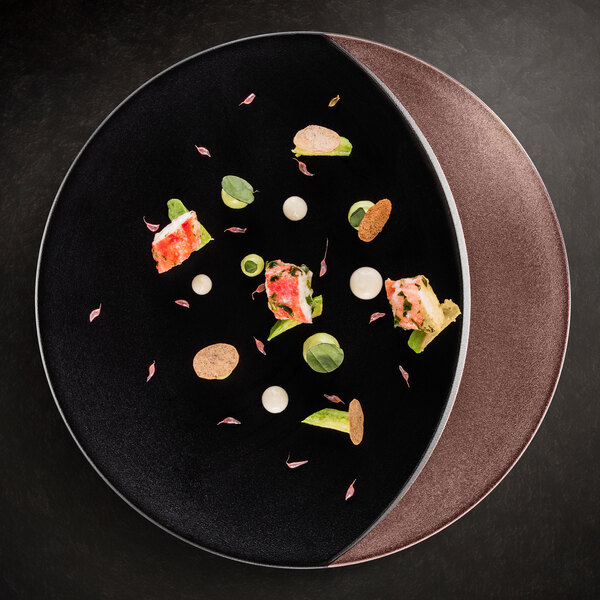 A RAK Porcelain black and bronze flat plate with food on it.
