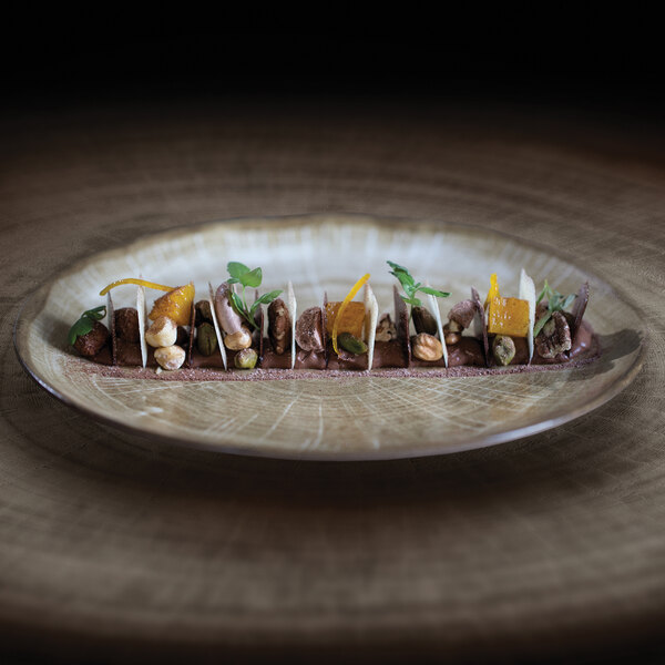 A RAK Porcelain Woodart Moss Green deep coupe plate with food on a table.