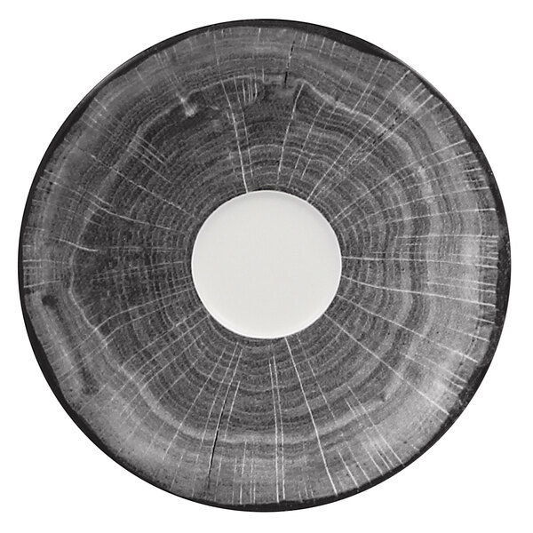 A white porcelain saucer with a circular beech design in the middle.